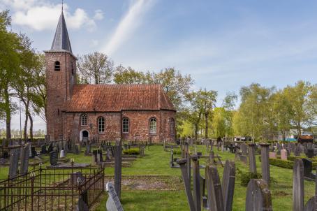 Brick church  with annexed bell tower and large graveyard in a field